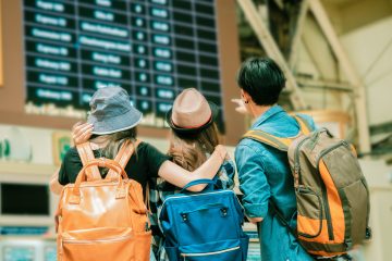 Three travellers viewing a time board together for travel.