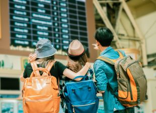 Three travellers viewing a time board together for travel.